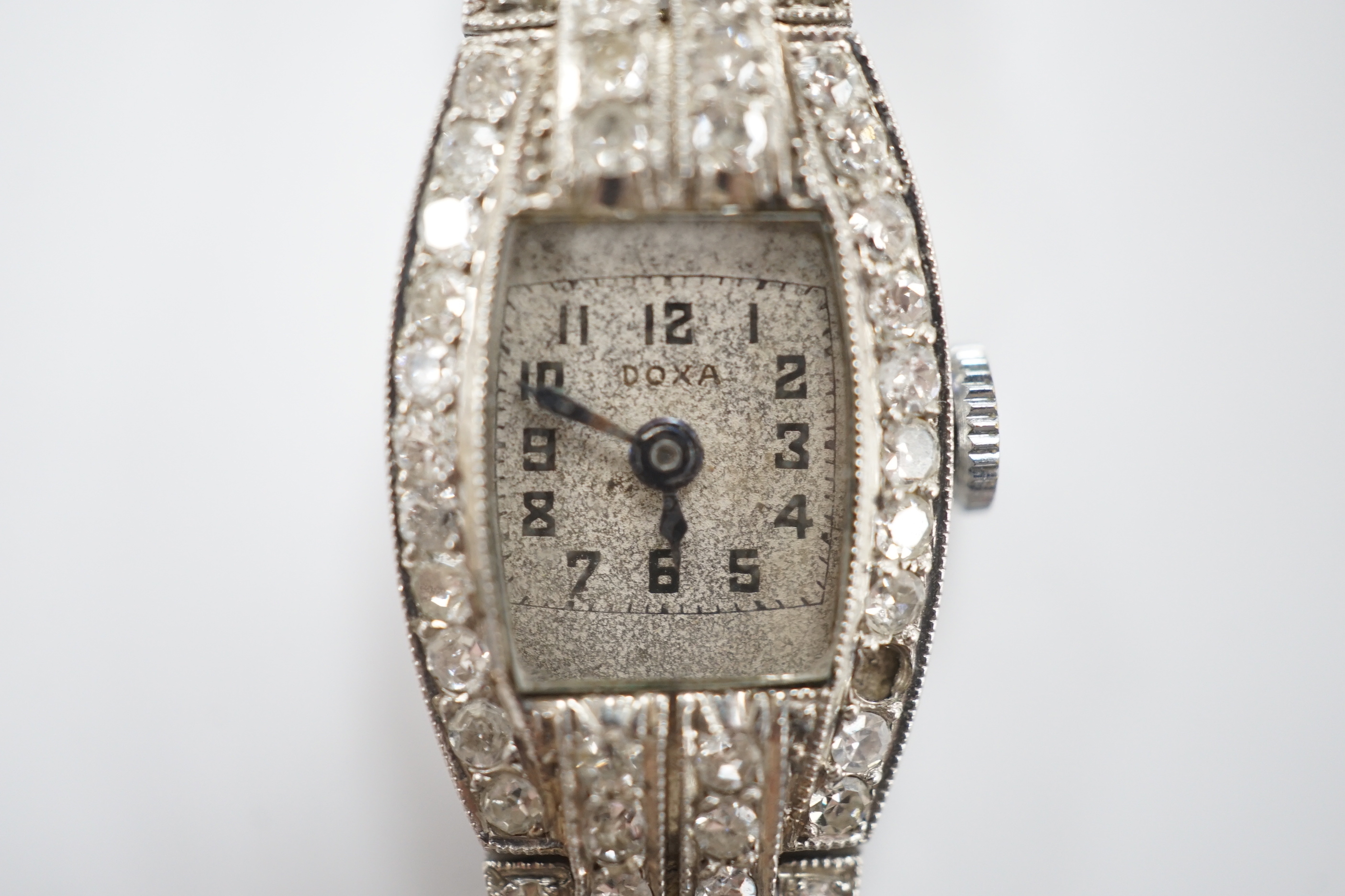 A lady's 1930's/1940's French white metal (platinum mark) and diamond cluster set manual wind cocktail watch, on a twin fabric strap, with metal clasp.